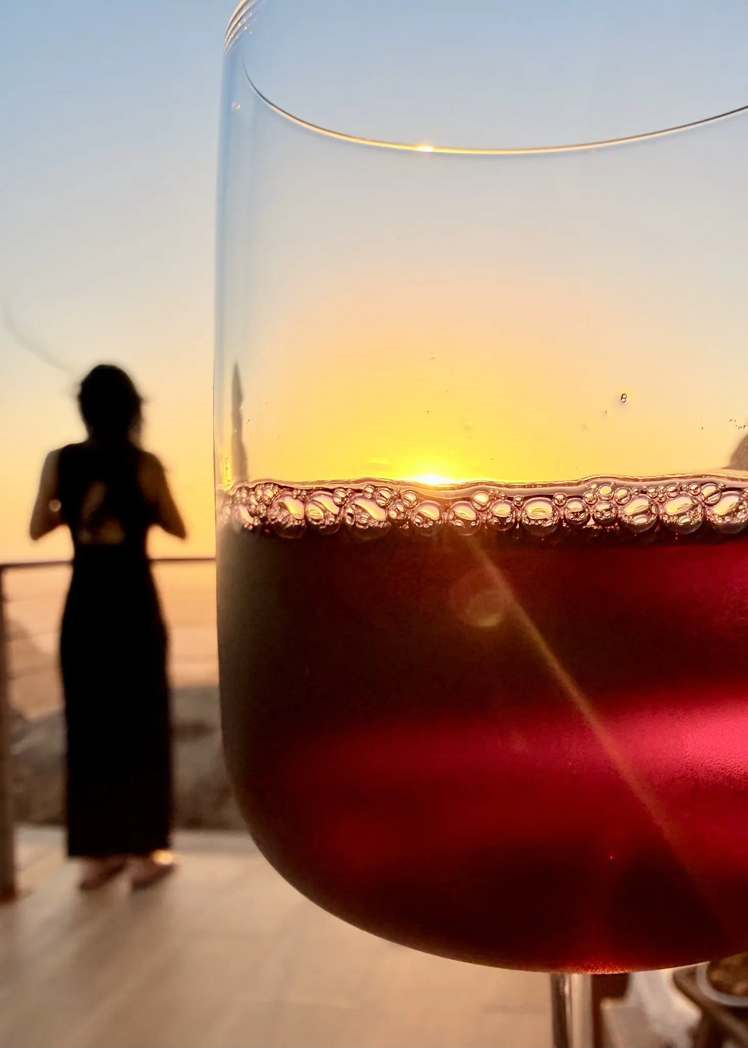 酒杯特写,背景是夕阳下的女子